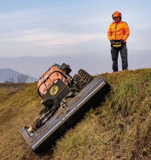 Homme contrôlant une tondeuse robotisée sur une pente